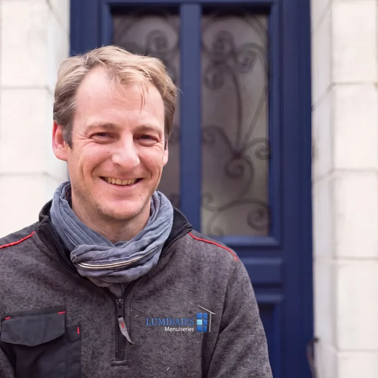 Portrait d'un menuisier Lumibaies devant une porte réalisée